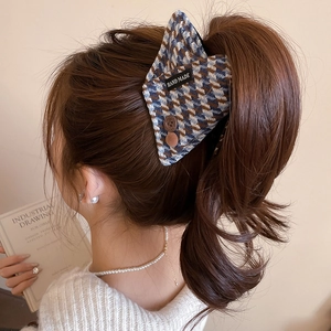 Close-up of a blue and brown houndstooth hair claw with handmade tag and buttons