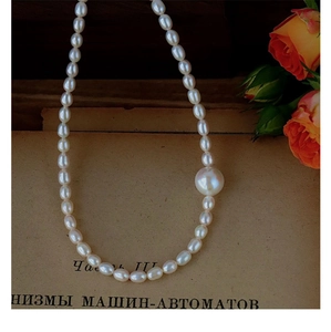 Detail of elegant freshwater pearl necklace resting on vintage paper with a rose