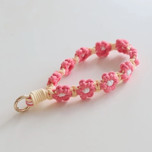 Detailed macro view of handmade pink crocheted daisy flower lanyard with gold metal ring clasp
