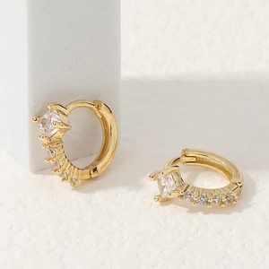 Elegantes pendientes de aro dorados con micro-pavé de circonitas sobre fondo de piedra blanca