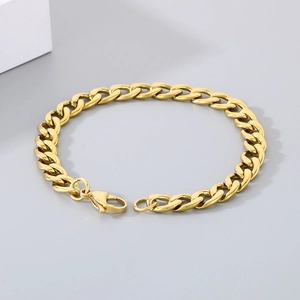 Close-up of golden Cuban link bracelet with lobster clasp on a minimalist background