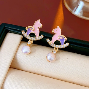 Detail of vintage rocking horse earrings with pink enamel, zircons, and pearl drops