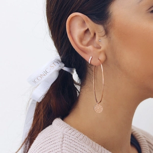Detail of s925 silver large hoop earring with rose gold embossed pendant worn by a model