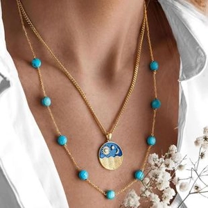 Close-up of bohemian layered gold necklace featuring blue beads and celestial pendants