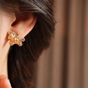 Detailansicht eines goldenen Einhorn-Ohrrings mit orangem Edelstein und Zirkonien