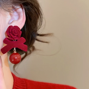 Gros plan de boucles d'oreilles rose rouge floqué avec nœud en velours et perle