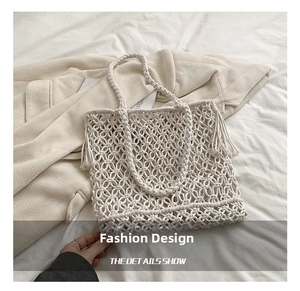 Detailed close-up of hollow-out woven tote bag with fringe tassels and woven handles