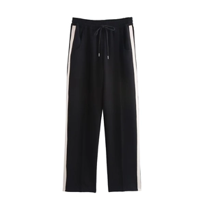 Detail view of black casual sports pants featuring white side stripes and drawstring waist