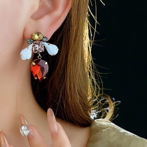 Close-up of vintage gold earrings with colorful crystals and red teardrop pendants