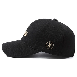 Classic black pineapple fabric baseball cap with golden M embroidery and side view detail