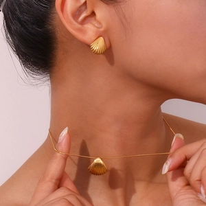 Dettaglio della collana con ciondolo a conchiglia dorata e orecchini sul modello