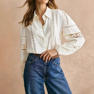 Close-up of elegant white long-sleeved shirt featuring geometric lace hollow stitching