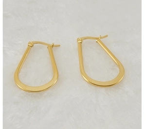 Detailed close-up of gold U-shaped hoop earrings on soft white plush background
