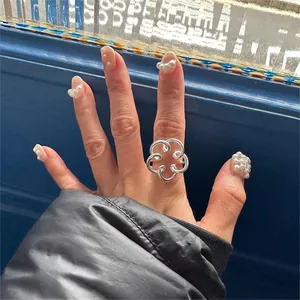 Detailed view of an openwork flower ring in 925 silver worn on a woman's finger