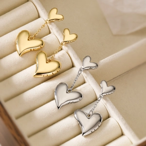 Minimalist 18K gold and silver heart drop earrings displayed in a luxury jewelry box