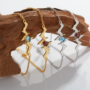 Detail of heart rate wave bracelets in gold and silver with red and blue gemstones
