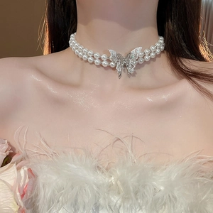 Close-up of double-layer pearl choker with a silver butterfly pendant on model neck