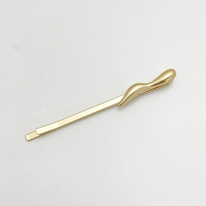 Detailed view of a gold alloy hairpin with streamlined wave decoration on white background