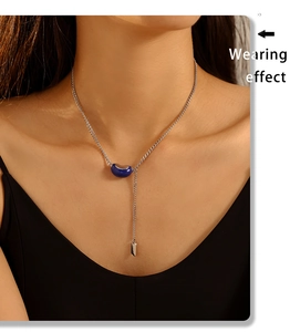 Close-up of model wearing silver necklace with blue bean pendant and Lucky tag