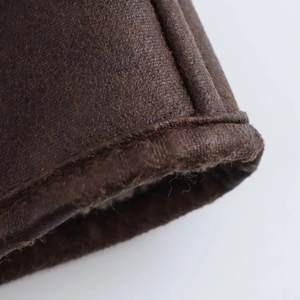 Close-up of stitching and faux leather texture on dark brown jacket cuff