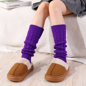 Detail of purple cable-knit leg warmers paired with brown fuzzy plush platform slippers