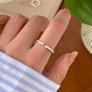 Close-up of minimalist silver twisted open ring showing elegant metallic texture