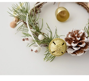 Close-up of Christmas wreath with pine cones, golden bells and white berries decoration