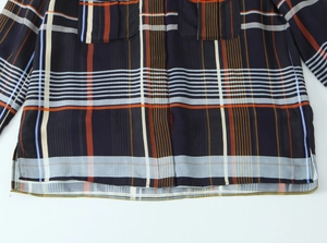 Detail eines Karohemds mit marineblau-orangefarbenem Muster und seitlichem Saumschlitz