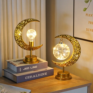 Détail de lampes lune en métal doré avec guirlandes LED blanc chaud sur un bureau en bois