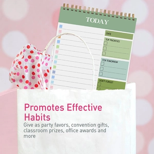 Green spiral daily planner inside a gift bag with polka dot paper and pink background