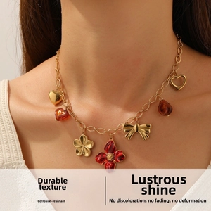 Détail d'un collier doré avec fleurs en émail rouge et pendentifs en forme de cœur