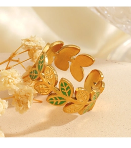 Macro shot of gold leaf ring with green enamel details and brushed metal texture