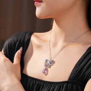 Close-up of elegant bow pendant necklace with purple zircon and sparkling crystals on model