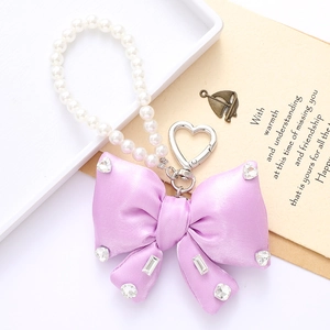 Detail of elegant purple satin bow keychain with sparkling rhinestones and white pearls