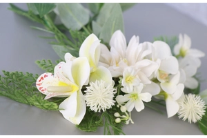 Close-up of white lilies and orchids floral hairpiece with green fern leaves for weddings