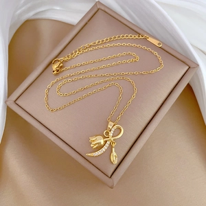 Macro shot of gold tulip pendant necklace with tiny diamonds on beige silk fabric