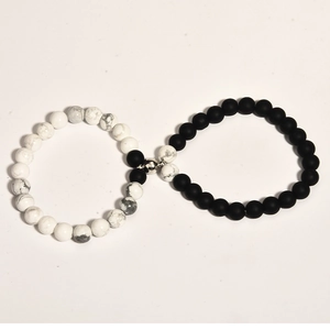 Macro detail of black and white magnetic couple bracelets formed in an infinity shape
