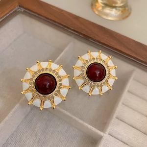Vintage style gold earrings with red gemstones and white enamel in a wooden jewelry box