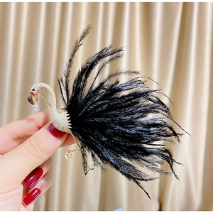 Detailed close-up of a golden flamingo brooch with crystals and soft black feathers