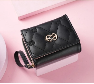 Close-up of black quilted leather wallet with floral embroidery and gold clasp detail