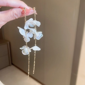 Vue détaillée de boucles d'oreilles pendantes aux pétales nacrés et chaînes dorées