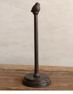 Dettaglio del portatovaglioli vintage in ghisa con uccellino su un tavolo di legno