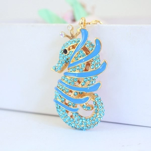 Cute golden seahorse keychain with blue rhinestones and enamel details on white base