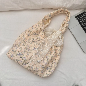 Close-up of floral canvas bag with white lace trim detail under natural sunlight