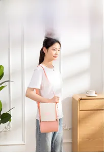 Lifestyle shot of model wearing a pink and white insulated lunch bag with shoulder strap