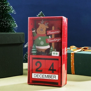 Wooden Christmas countdown calendar with reindeer figure and red date blocks on a desk