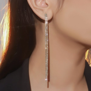 Close-up of elegant long tassel earrings with sparkling rhinestones on model