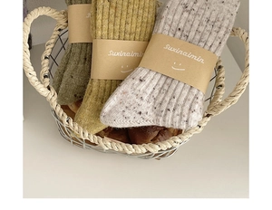 Close-up of three pairs of thick wool socks in warm tones placed in a metal basket