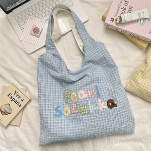 Detailed shot of light blue plaid tote bag featuring colorful Pearl Sozakka embroidery