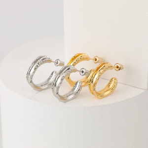 Detail view of gold and silver C-shaped hoop earrings with unique molten lava texture
